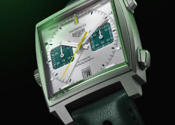 A close-up of the Green Dial TAG Heuer Monaco automatic chronograph watch with a square face. The watch features green chronograph subdials, silver indices and hands, and a date display at the 6 o'clock position. It is paired with a green perforated leather strap. | MAKE1M