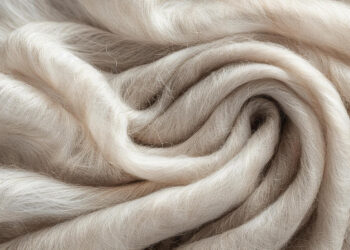 Close-up of soft, wavy, beige fibers arranged in gentle folds and swirls, highlighting their smooth, silky texture and fine strands. | MAKE1M