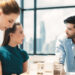 Three people are having a discussion in a bright office with large windows. Two women and one man are focused on a table with architectural models, with a cityscape visible in the background. | MAKE1M