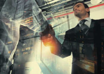 Two businessmen in suits shaking hands, with a double exposure effect showing modern office buildings and city lights, symbolizing partnership and corporate collaboration. | MAKE1M