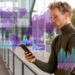A man in glasses and a turtleneck looks at his smartphone outdoors. Overlay graphics show digital data, charts, and a world map, suggesting analysis or global connectivity. | MAKE1M