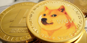 A close-up of several cryptocurrency coins, with a prominent Dogecoin featuring the Shiba Inu dog meme, surrounded by other coins and part of a U.S. dollar bill visible underneath. | MAKE1M
