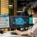 A woman works at a desk with two monitors; one displays AI statistics and data, while the other shows a digital brain graphic, suggesting she is analyzing artificial intelligence or machine learning information. | MAKE1M